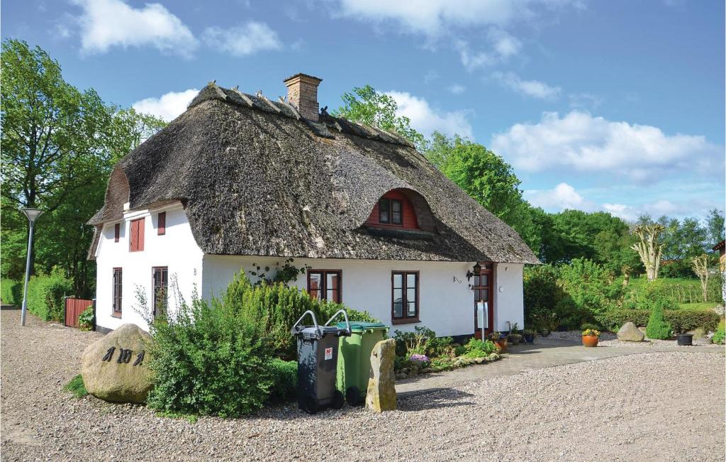 una pequeña casa blanca con techo de paja en Amazing Home In Krus With Kitchen, en Kruså