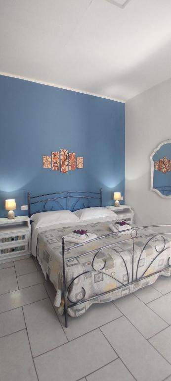 a bedroom with a bed with a blue wall at Estía Holidays Apartments - Taormina in Taormina