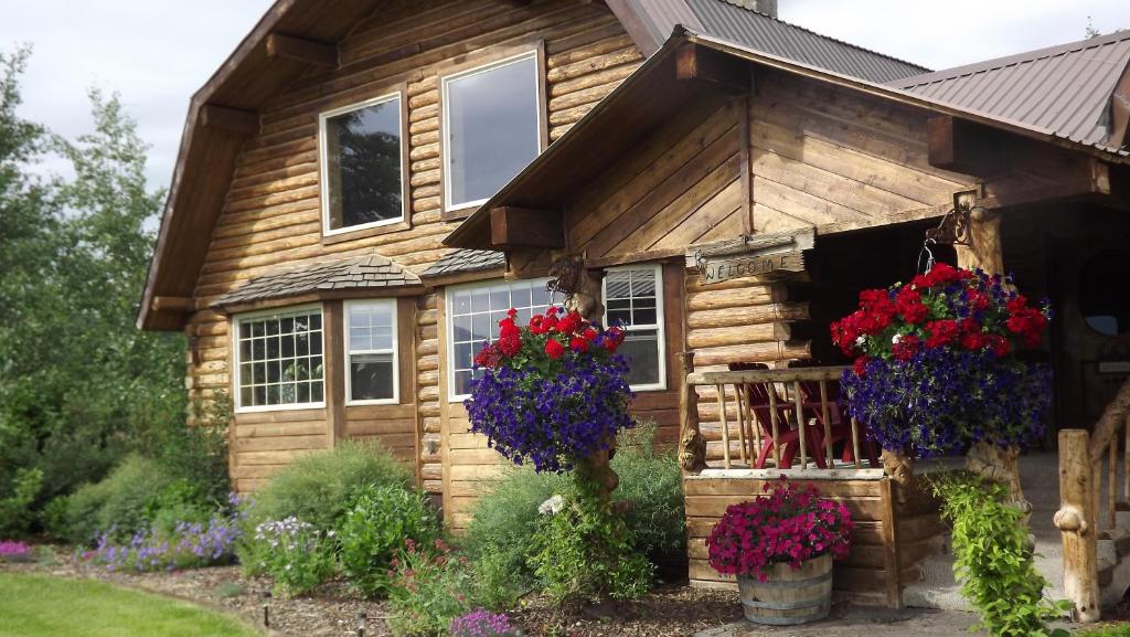 a wooden house with flowers in front of it at Fin and Feather Inn in Victor
