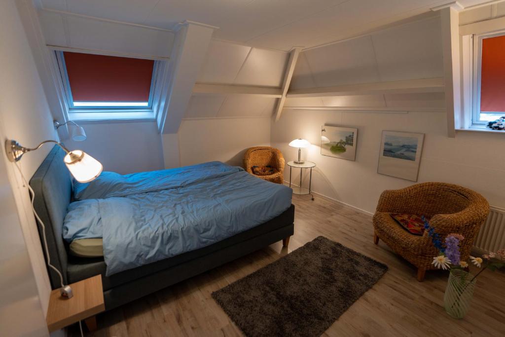 a bedroom with a bed and two wicker chairs at de lange adem in Millingen aan de Rijn
