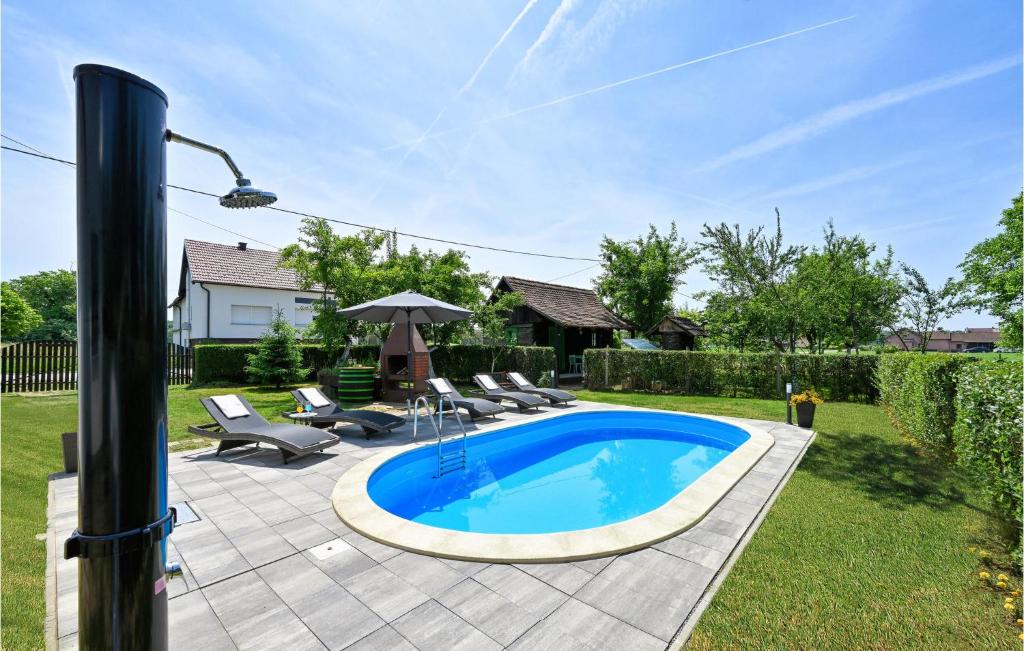 Gudovac的住宿－Nice Home In Gudovac With Kitchen，庭院内的游泳池配有椅子和遮阳伞