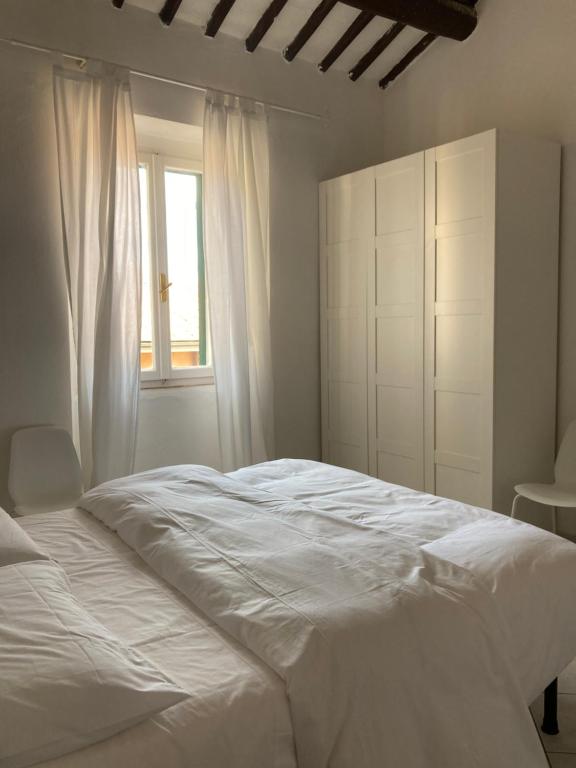 1 dormitorio con cama blanca y ventana en La casina, en Marciana Marina