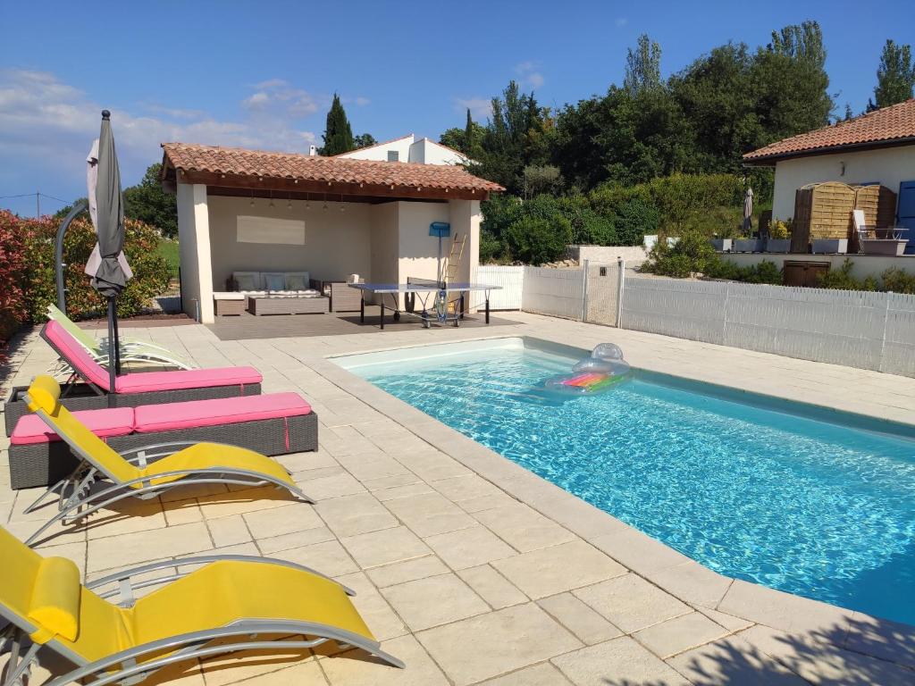 - une piscine avec 2 chaises et un parasol dans l'établissement L'Ansolanette - Chambre d'hôtes, à Fuveau