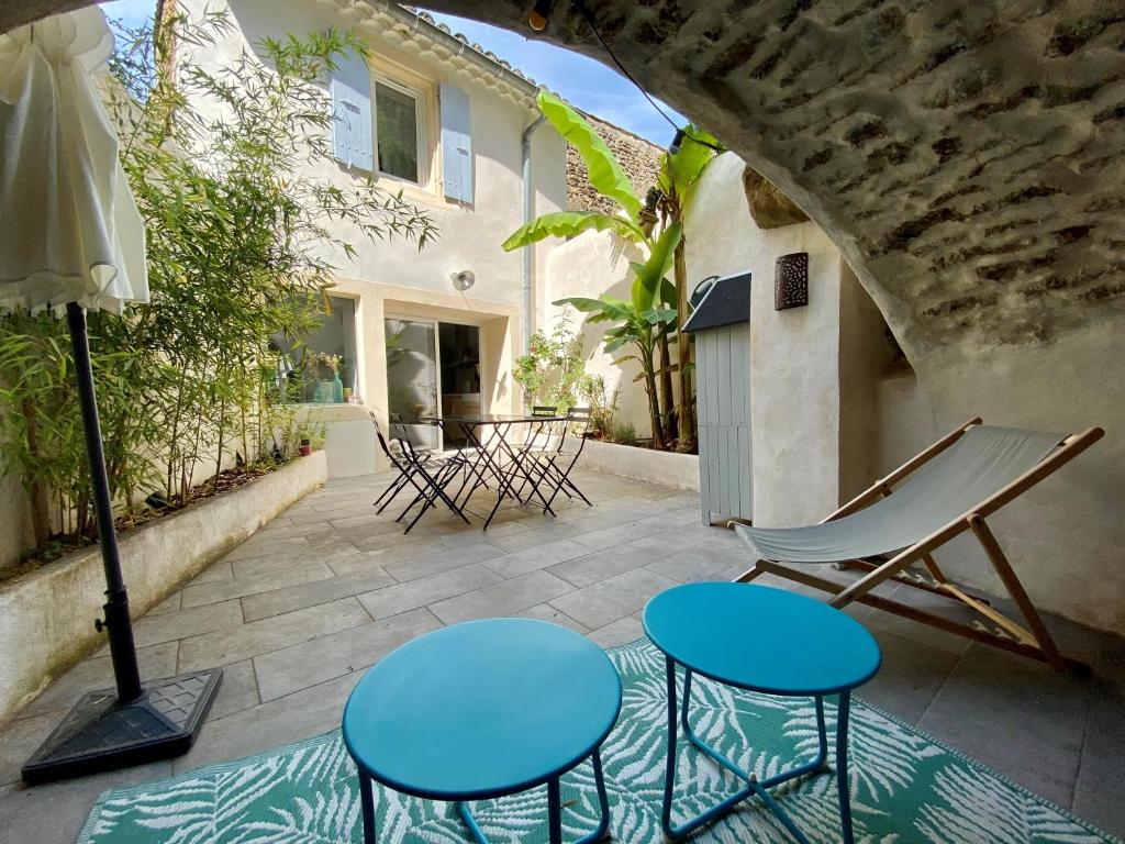um pátio com cadeiras e mesas e uma casa em La Maison Rose em Grignan