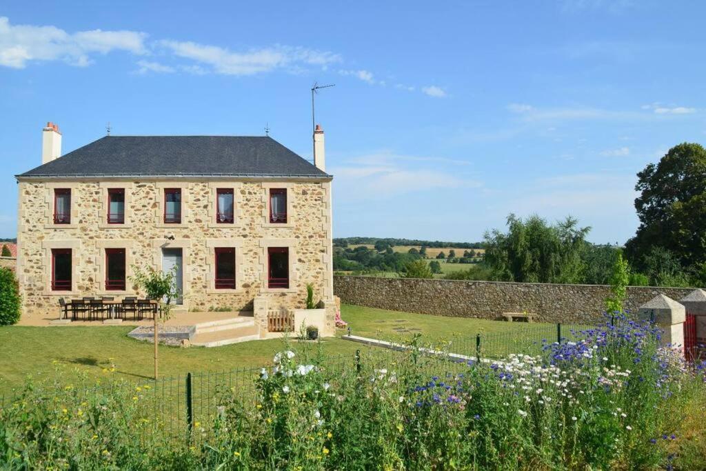 una gran casa de piedra con un jardín delante de ella en Gîte La Dortière s'Amuse, magnifique maison de maître 12min du Puy du Fo en Sevremont