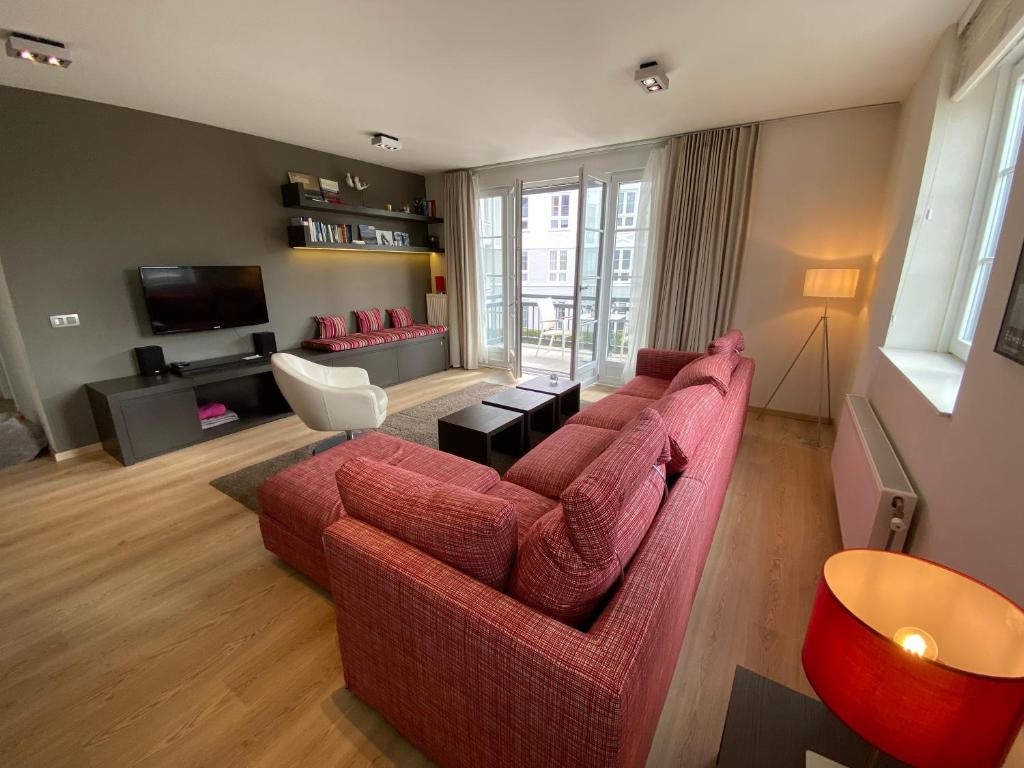 uma sala de estar com um sofá vermelho e uma televisão em Edward Hopper Suite, Duinhof 3-9-7, spacious apartment near the beach with sunny balcony em Cadzand