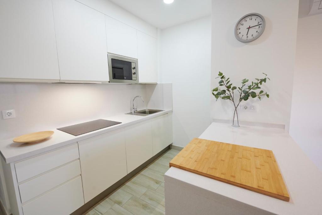a kitchen with white cabinets and a clock on the wall at ABLANCAS - La Restinga in La Restinga