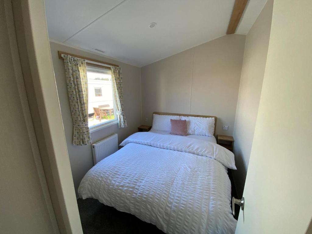 a small bedroom with a bed and a window at 3 Bed Static Caravan in Morecambe in Morecambe