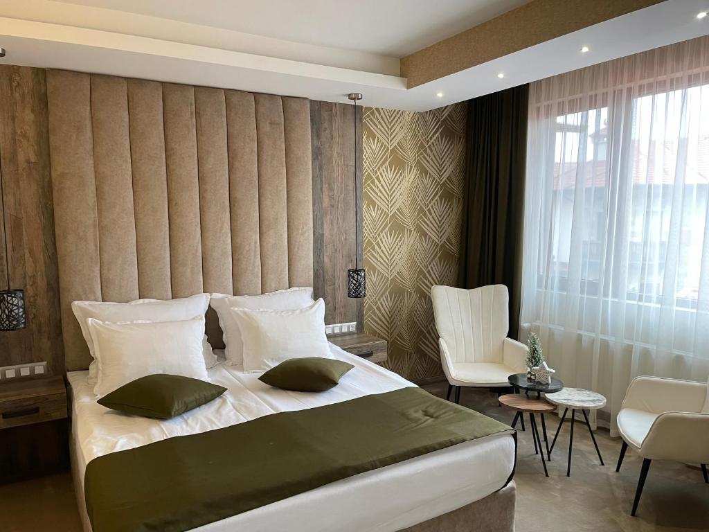 um quarto com uma cama grande e uma cadeira em Paradise SPA Hotel em Tsigov Chark