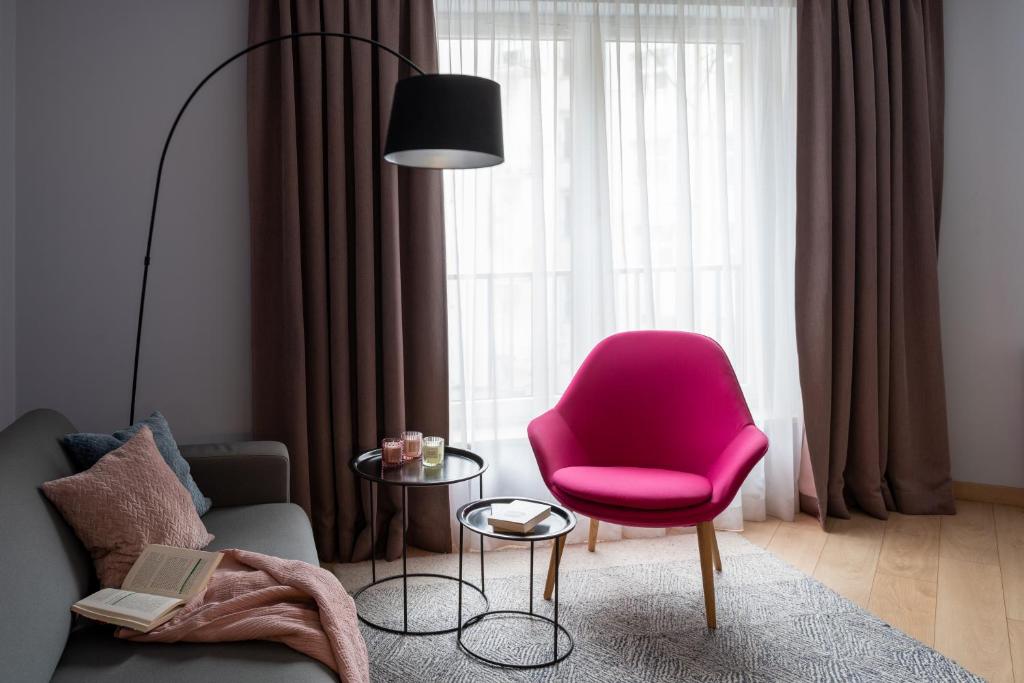 een woonkamer met een roze stoel en een tafel bij Happy House Apartamenty in Krakau