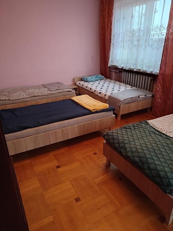three beds in a room with a wooden floor at Warszawska 