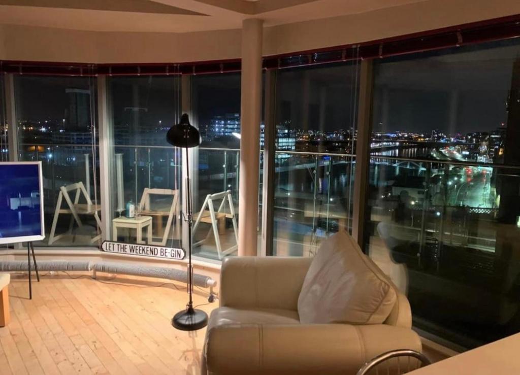 a living room with a couch and a large window at Designer Penthouse with Riverviews - G1 Glasgow City Centre, 3 Bedrooms, 2 Bathrooms, 1 Living room / Kitchen. Full Floor, Wrap Around Terrace, Panoramic Views, Off Central Station / Buchanan Street in Glasgow
