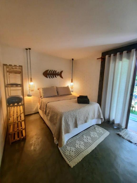 een slaapkamer met een bed en een groot raam bij Estudio Lirios seu cantinho ecológico na natureza in Marau