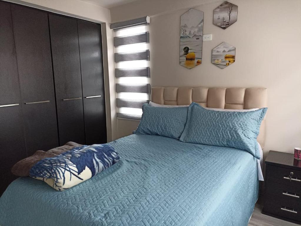 1 dormitorio con 1 cama con edredón azul en Lujoso Apartamento Frente al Estadio Bellavista, en Ambato