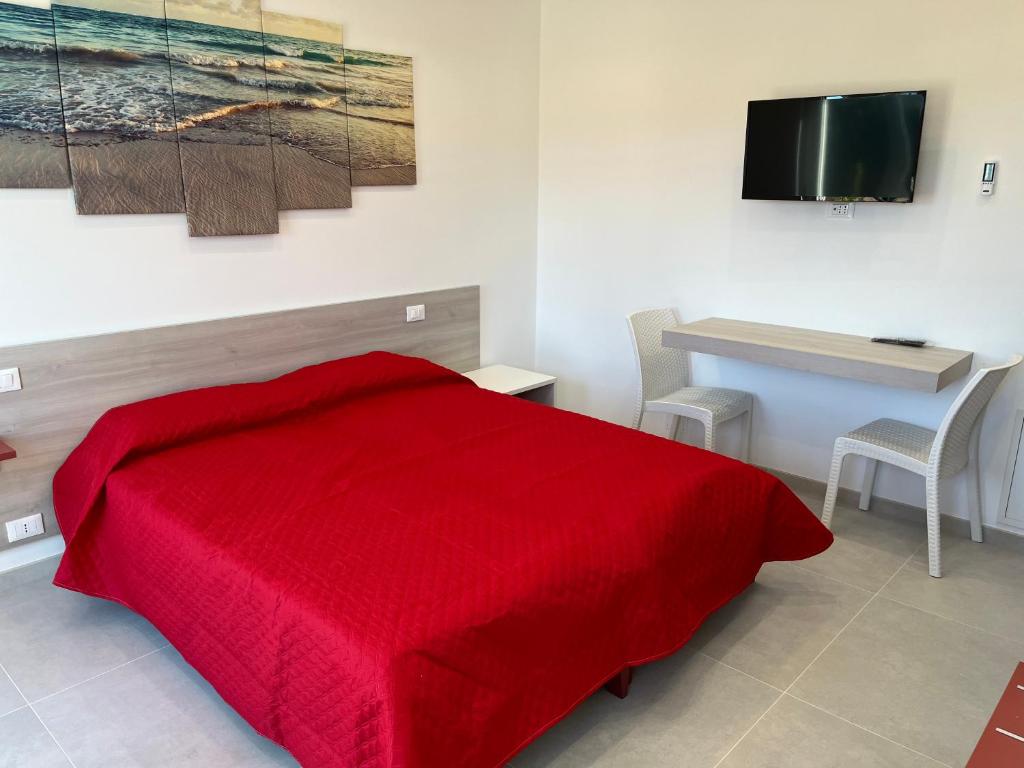 - une chambre avec un lit rouge et un bureau dans l'établissement B&B Casa Nicole, à Peschici