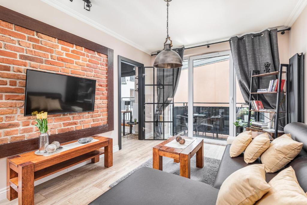 a living room with a brick wall and a tv at Comfort Studio River House in Szczecin