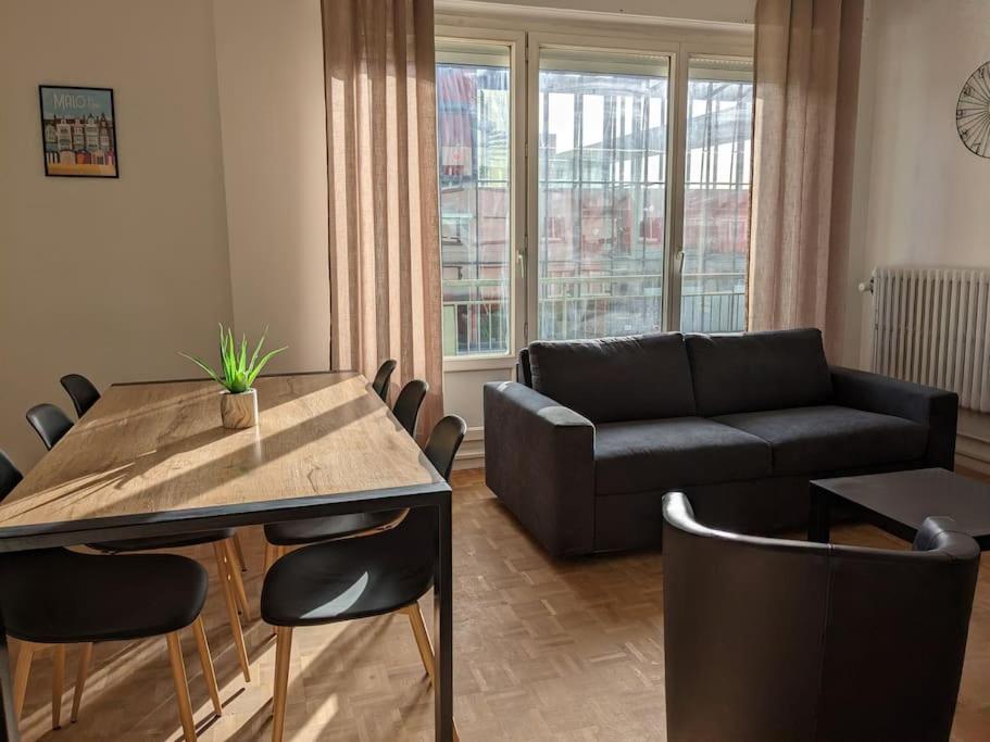 uma sala de estar com uma mesa e um sofá em L'Effet-Mer em Dunkerque