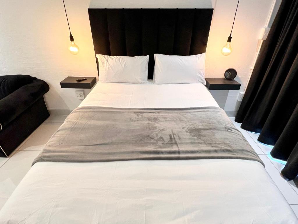 um quarto com uma grande cama branca e uma cabeceira preta em Industrial CHIC Apartment 113 em Joanesburgo