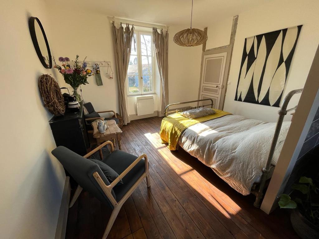 a bedroom with a bed and a chair and a window at Le Brasseur Logements in Saint-Caprais