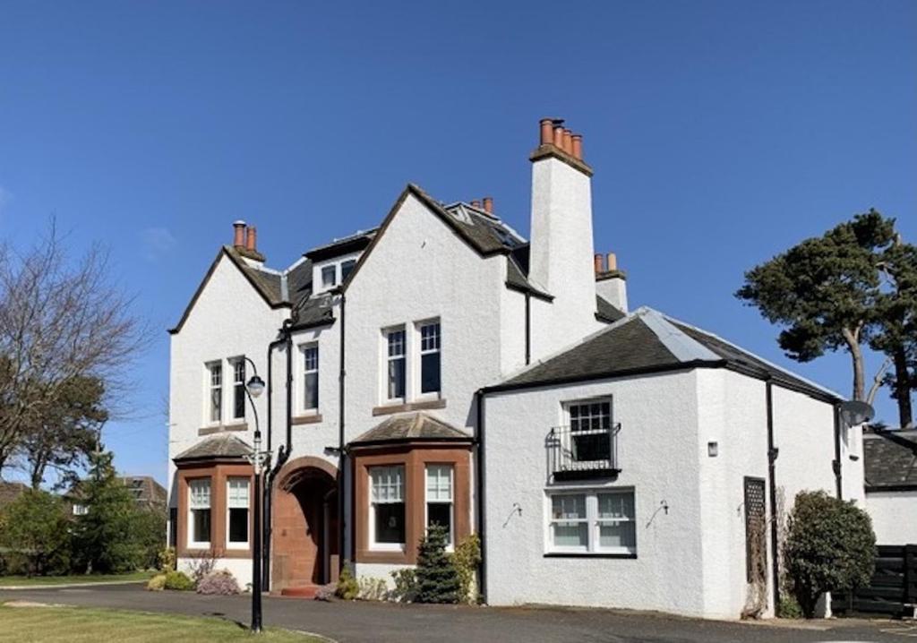 een groot wit huis met een schoorsteen bij Pinewood Country House in Leuchars