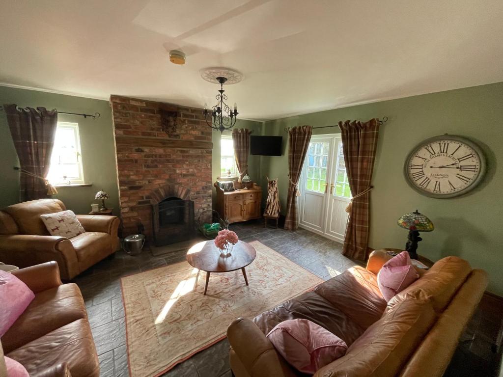 een woonkamer met een bank en een klok aan de muur bij Eastfield Cottage in Leven