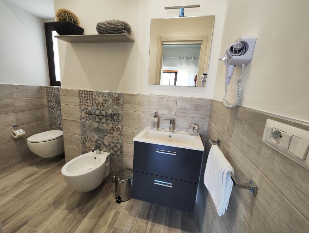 un bagno con lavandino, water e specchio di B&B CESARE'S Guests ad Acitrezza