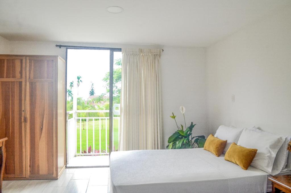 ein Schlafzimmer mit einem weißen Bett und einem großen Fenster in der Unterkunft Hotel Santa Isabel in Pereira