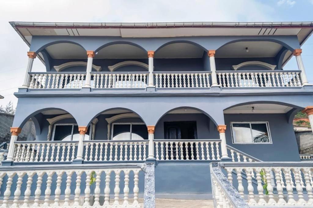 a blue house with a white balcony at M & B Residence in Freetown