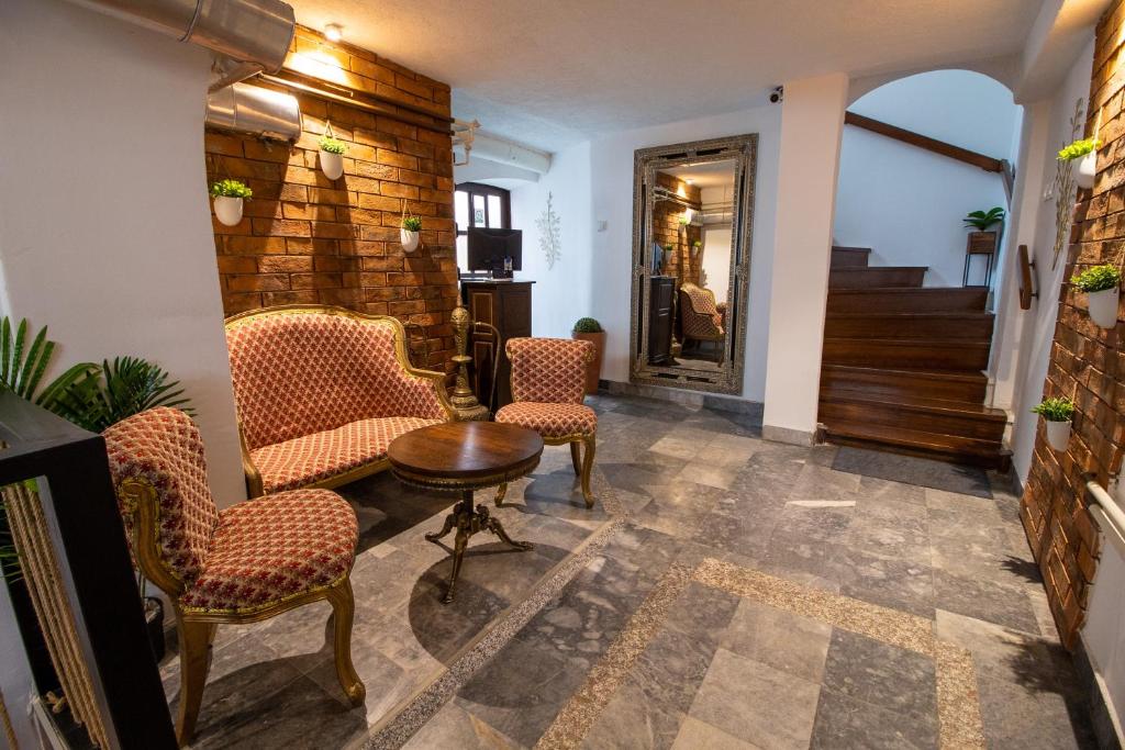 a lobby with chairs and a table and a staircase at Rooms BAUMAN in Osijek