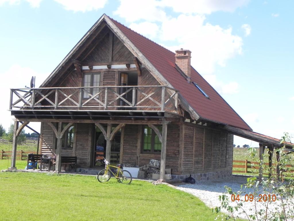 a large wooden house with a bike parked in front of it at Dom Nad Jeziorem Łąkorz in Łąkorz