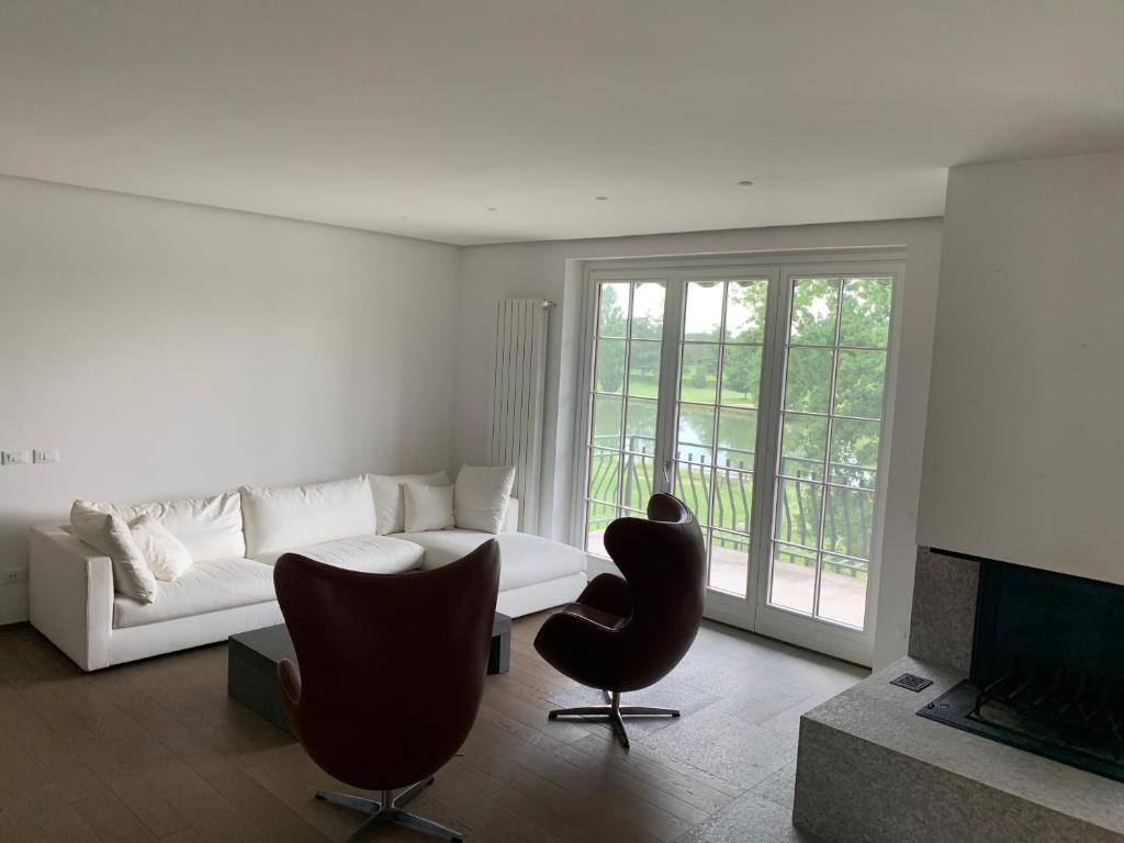 Sala de estar blanca con sofá y silla en Arianna Golf - Appartamento con camino e sauna golf club Margara en Fubine