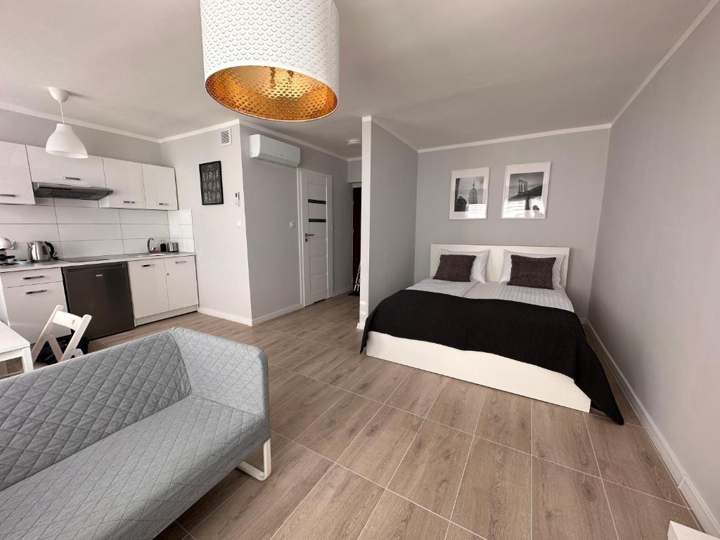 Cet appartement comprend une chambre avec un lit et un canapé ainsi qu'une cuisine. dans l'établissement APARTAMENT OŚ. ZŁOTE 5F, à Dzierżoniów