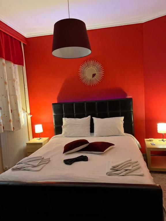 1 Schlafzimmer mit einer roten Wand und 1 Bett mit 2 Handtüchern in der Unterkunft Sweet luxury in Thessaloniki