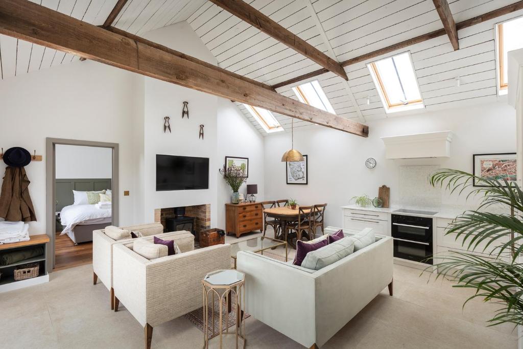 a living room with white furniture and a bedroom at Linseed Barn- Stamford Holiday Cottages in Stamford
