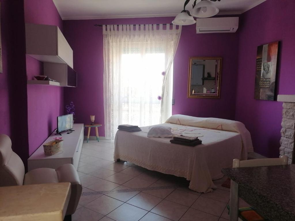 una camera da letto con pareti viola, un letto e una finestra di Monolocale a Calangianus