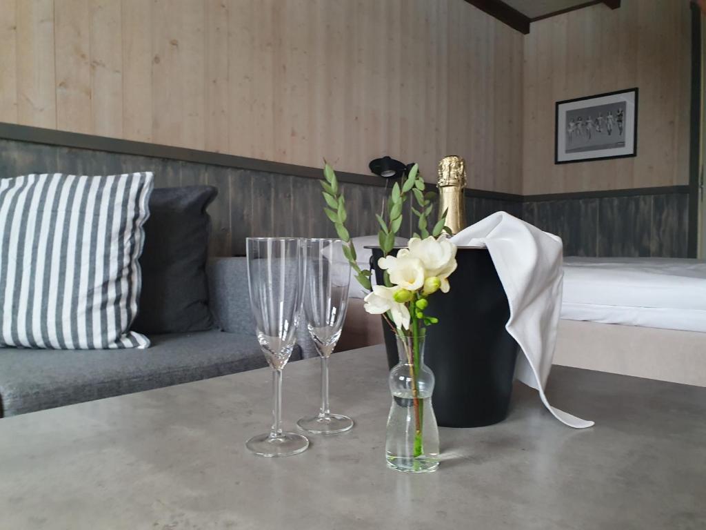 ウレグルンドにあるEpokgårdenのワイングラス2杯と花のテーブル