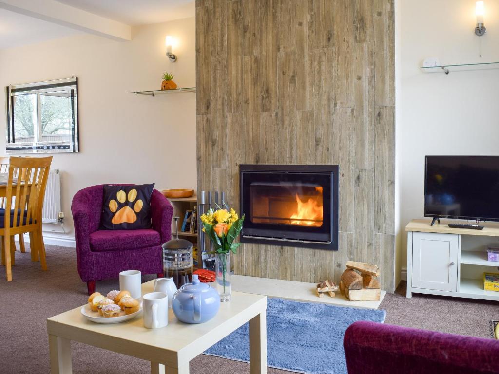 a living room with a fireplace and purple chairs at Baileys Tavern in Wartnaby