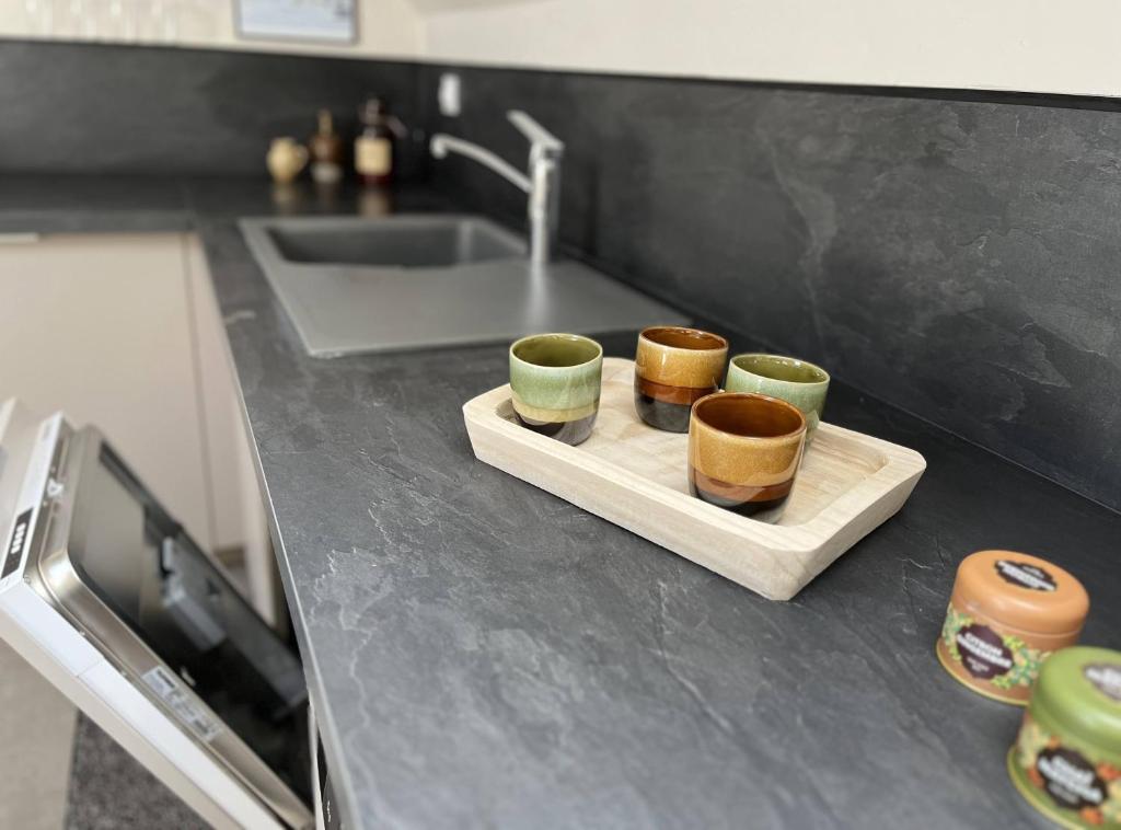 trois tasses assises sur une planche de découpe sur un comptoir de cuisine dans l'établissement Les gîtes de La Pellerie - 2 piscines & spa Jacuzzi - Touraine - 3 gîtes - familial, calme, campagne, à Saint-Branchs