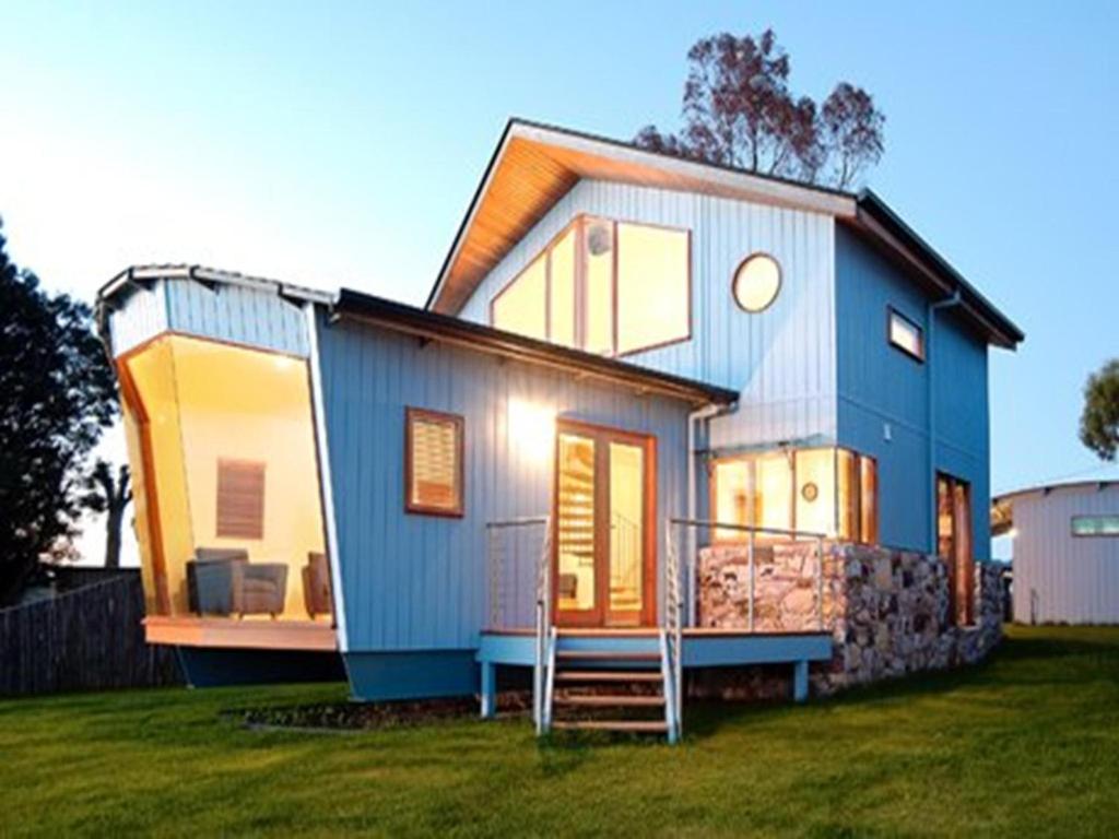 a blue house on a grassy field at Wheelhouse Apartments in Strahan