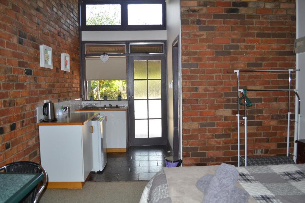 a kitchen with a sink and a brick wall at Colonial Motel in Omeo