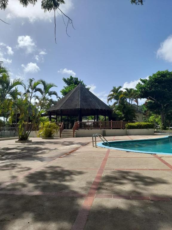 a swimming pool with a gazebo in a park at Tree House Luxe in Saint Annʼs Bay