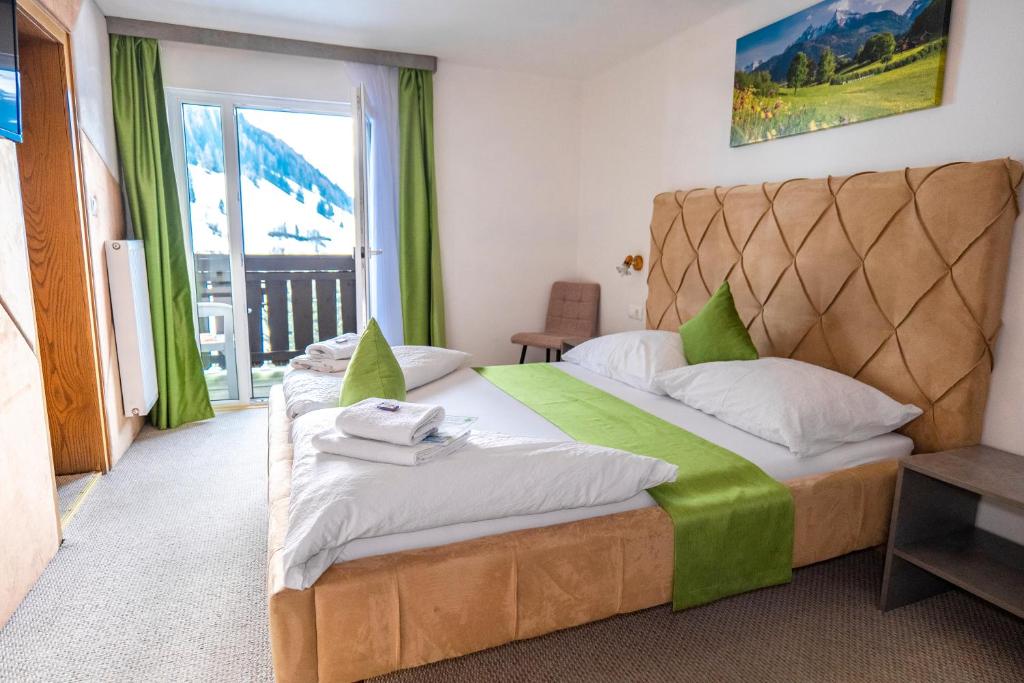 um quarto com uma cama grande e uma janela em Hotel Sonnhof Rauris em Rauris