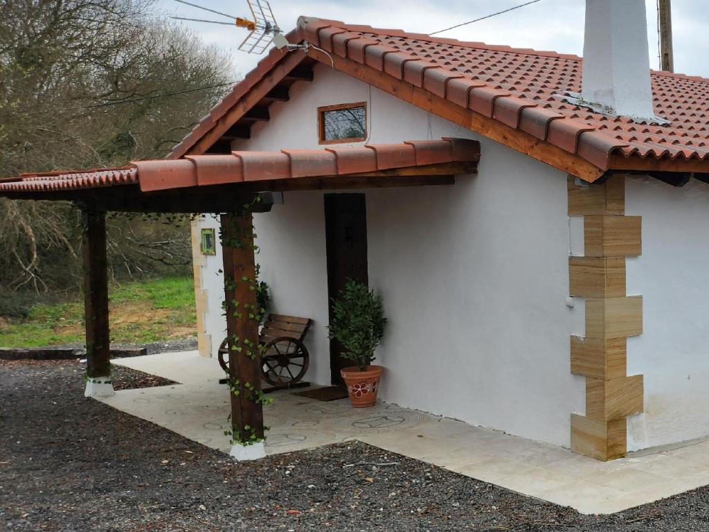 una pequeña casa blanca con techo rojo en La cabaña de Seña en Laredo