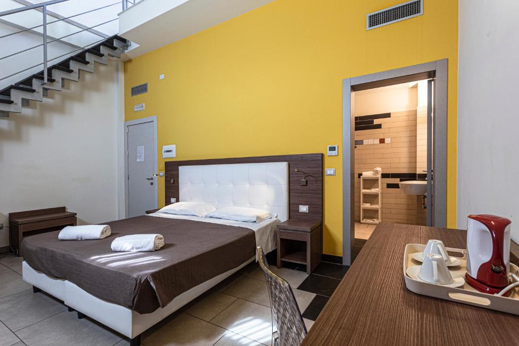 Hotel Don Giovanni في أفولا: غرفة نوم بسرير وطاولة وحمام