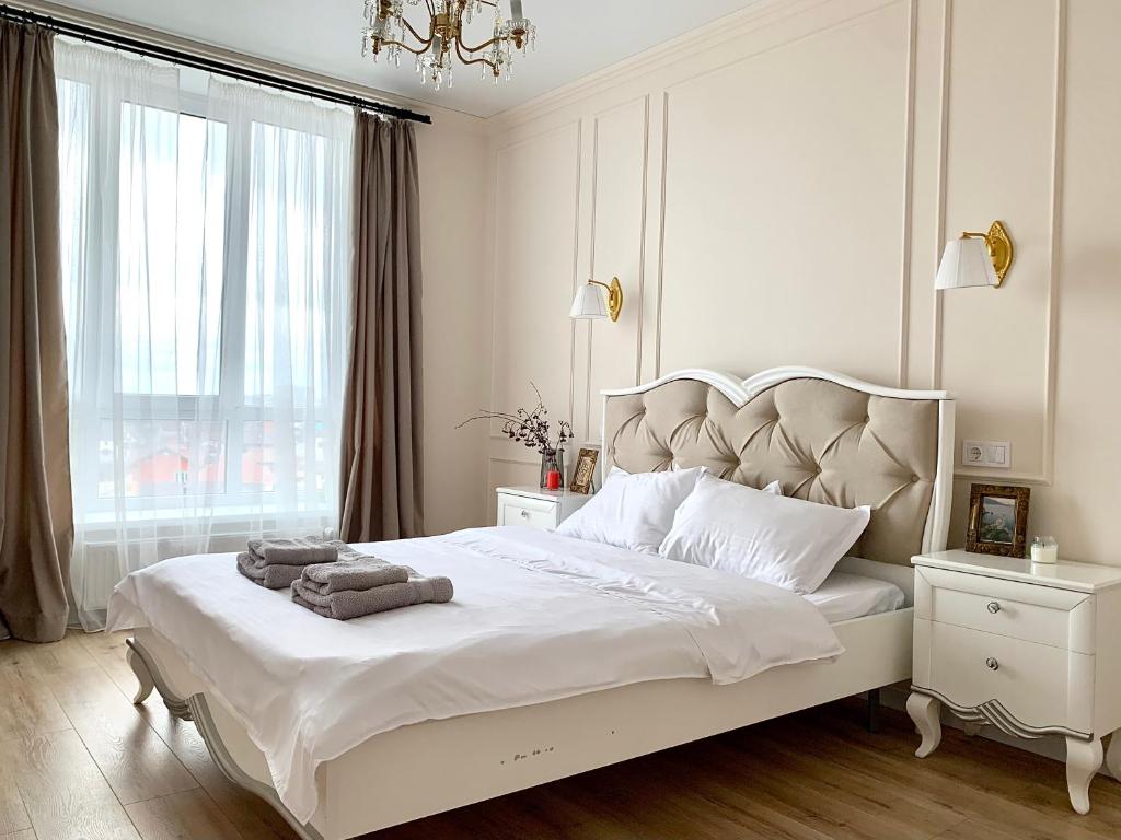 ein weißes Schlafzimmer mit einem großen Bett mit Handtüchern darauf in der Unterkunft Французская квартира с закатами ЖК Парк Фонтанов in Fontanka