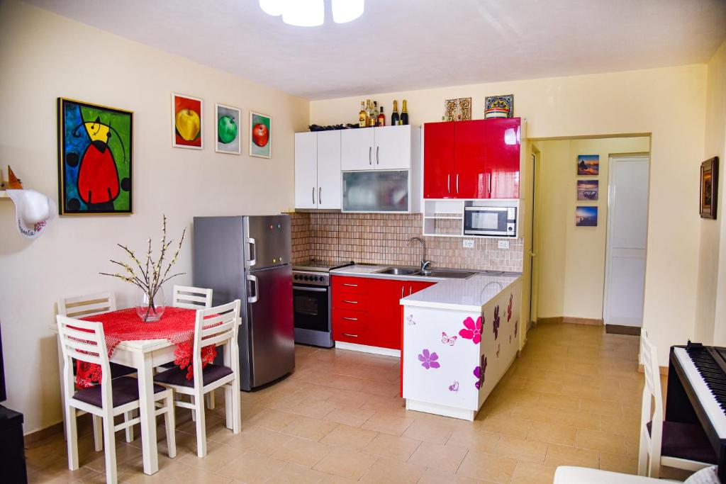 uma cozinha com armários vermelhos e uma mesa e cadeiras vermelhas em White Sea View Apartment Velipoje em Velipojë