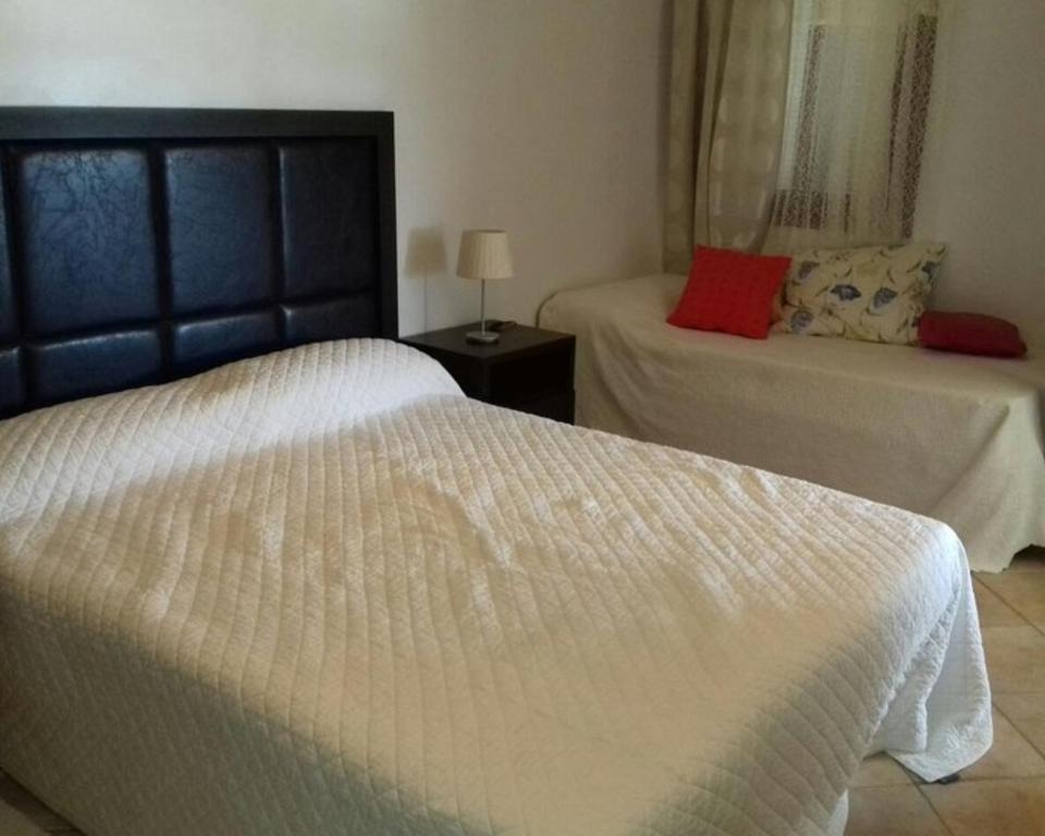 una camera con 2 letti con lenzuola bianche e cuscini rossi di EDyar nakhil Appartement a Marrakech