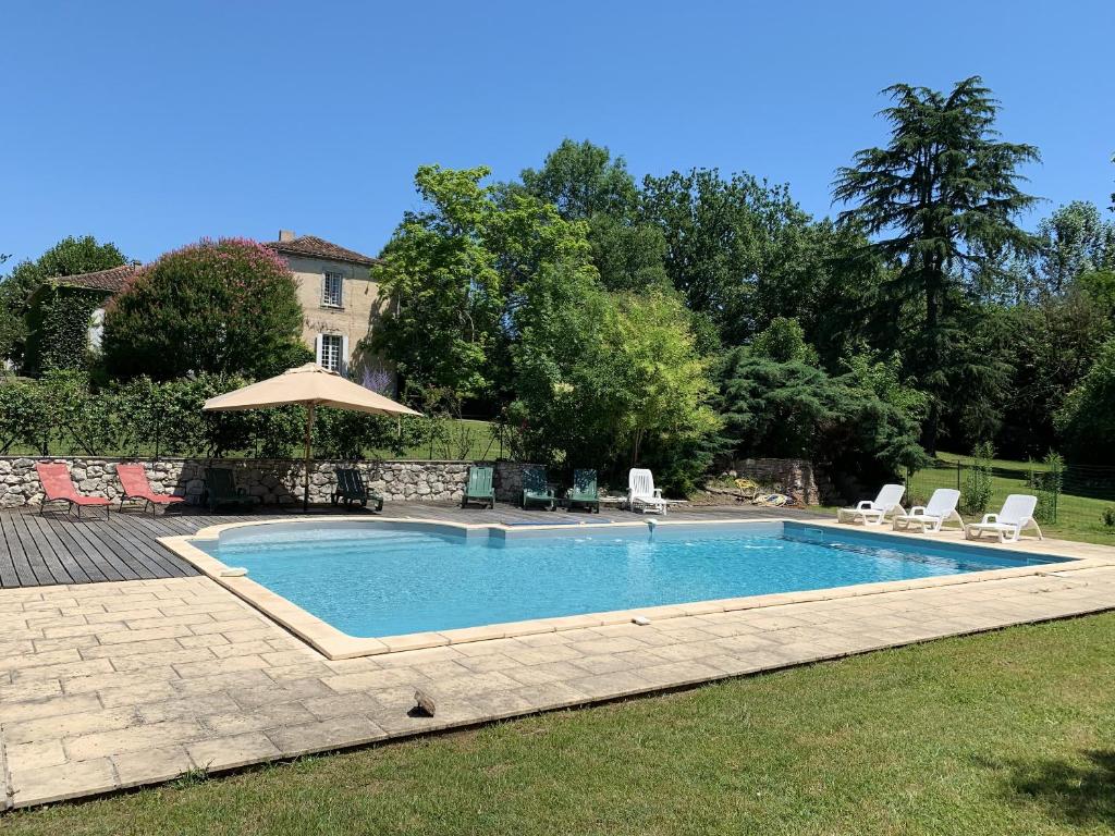 a swimming pool with chairs and an umbrella at Villa de 10 chambres avec vue sur la ville piscine privee et jardin amenage a Villeneuve sur Lot in Villeneuve-sur-Lot