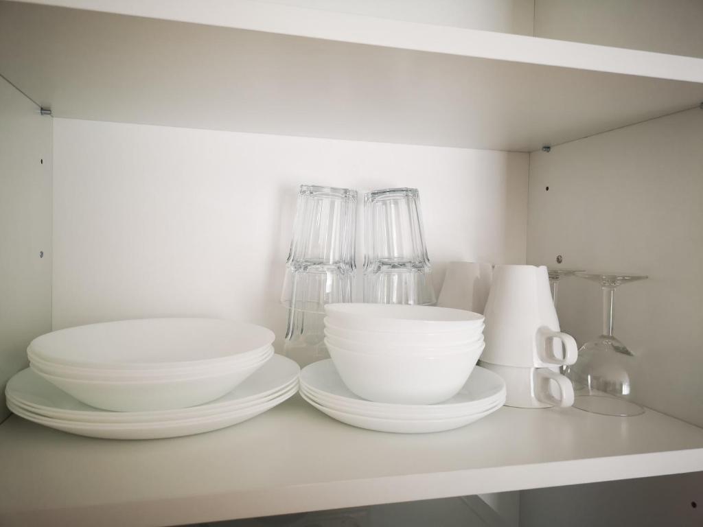 a white shelf with bowls and other dishes on it at Apartamentai centre in Klaipėda