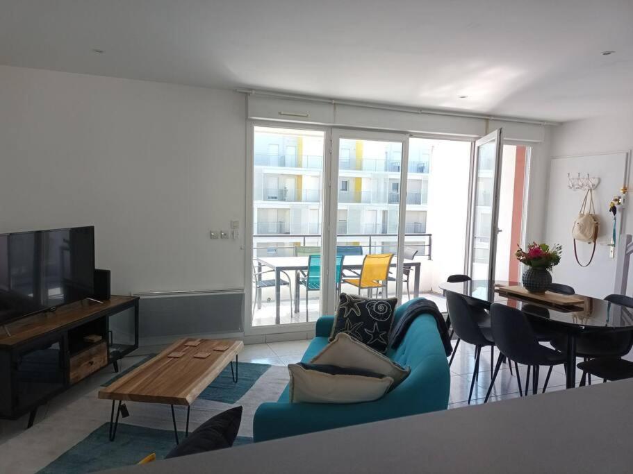 un salon avec un canapé bleu et une table dans l'établissement Bel appartement à Royan, tout à pied., à Royan